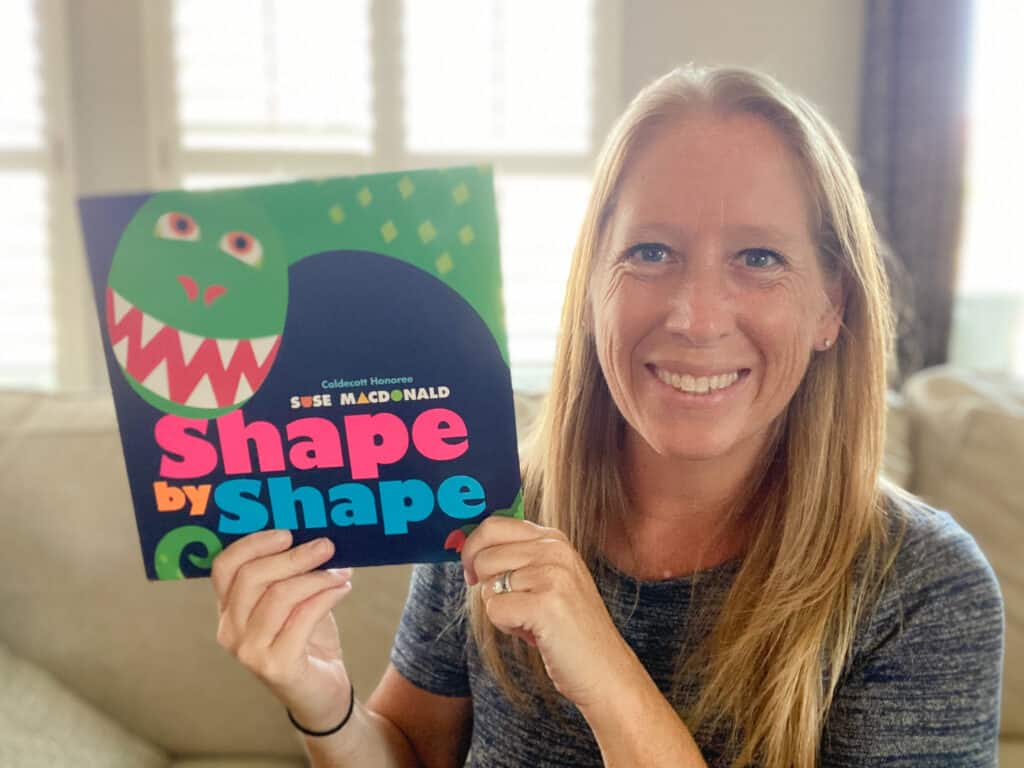 white woman holding the book Shape by Shape by Suse Macdonald