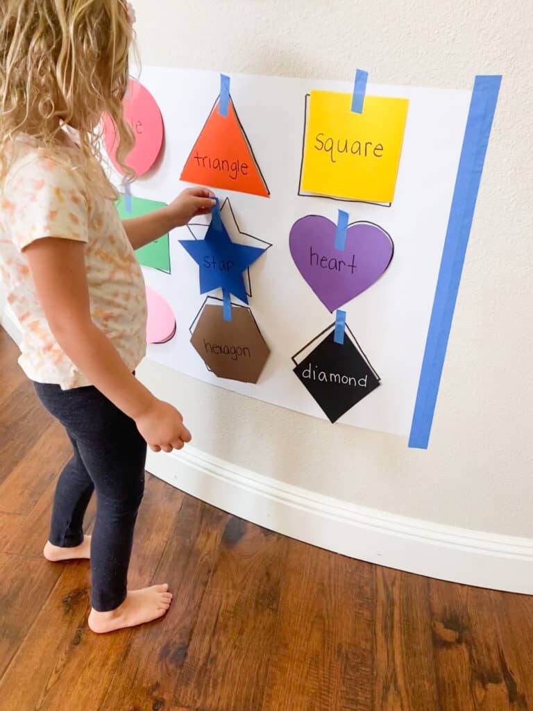 girl sticking a blue paper star onto the wall and matching it to a star shape