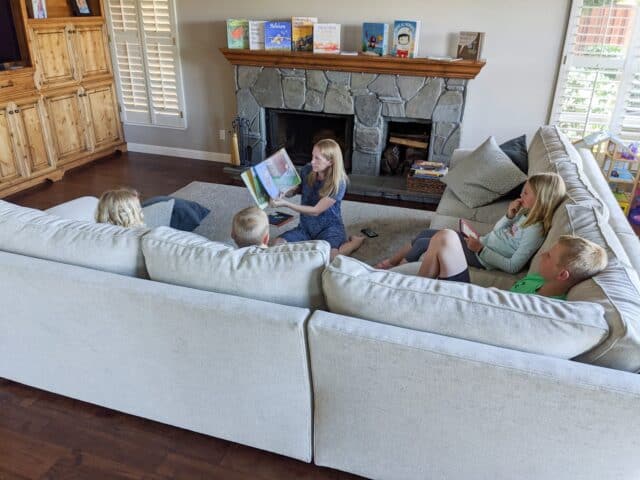 woman reading a book with four kids listening on the couch