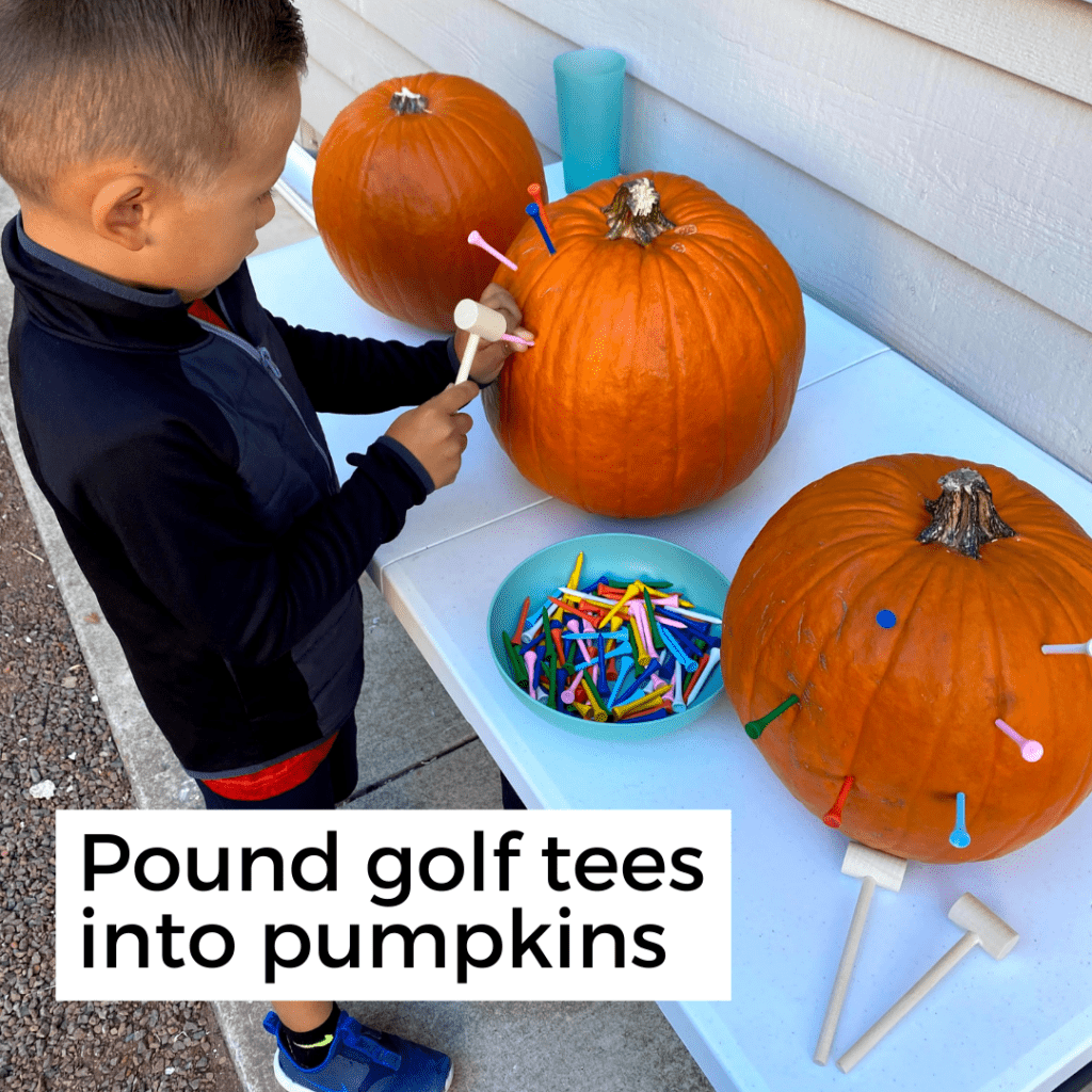 boy pounding colorful golf tees into a pumpkin