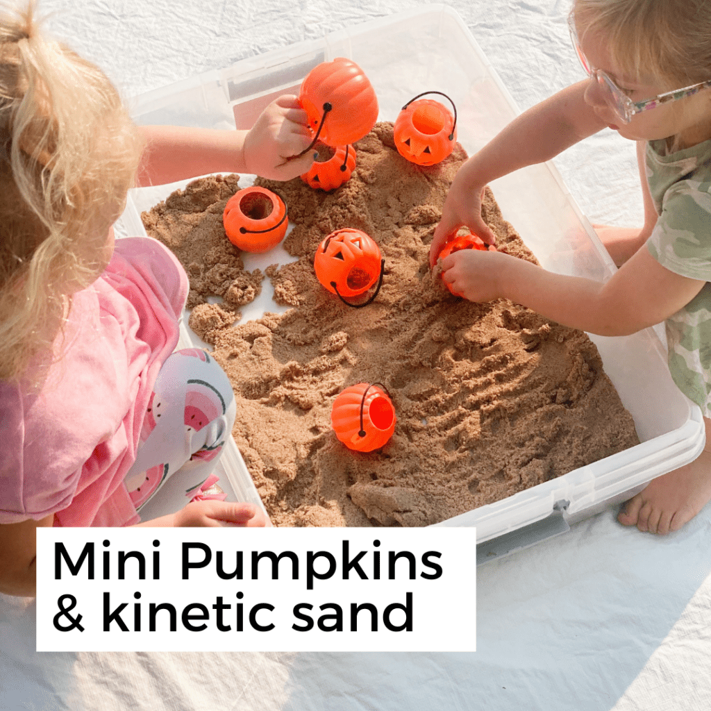 two kids playing with kinetic sand and plastic pumpkins