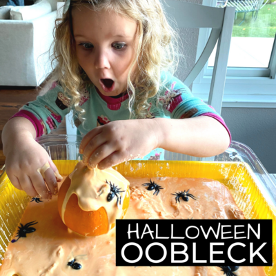 Girl playing with orange oobleck and plastic spiders